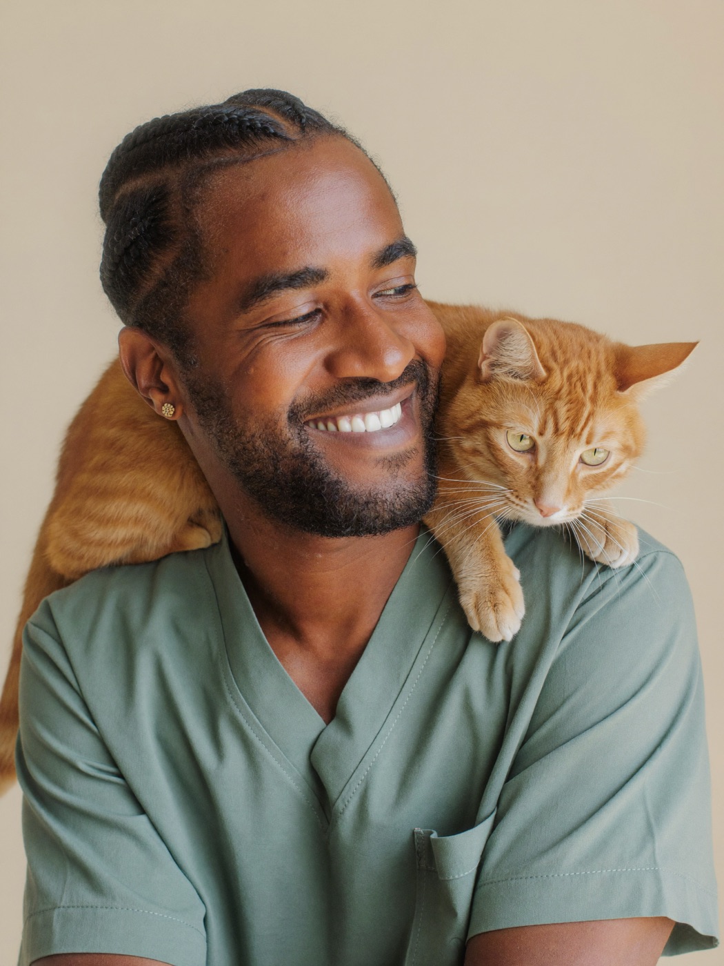 Dr. Malik Osei, associate veterinarian at Brightpaw Veterinary, holding an orange tabby cat.