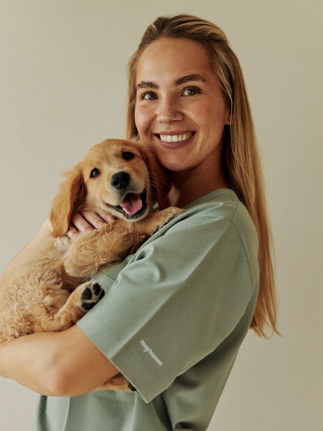 Dr. Naomi Voss, founder and lead veterinarian at Brightpaw Veterinary, holding a golden retriever puppy.